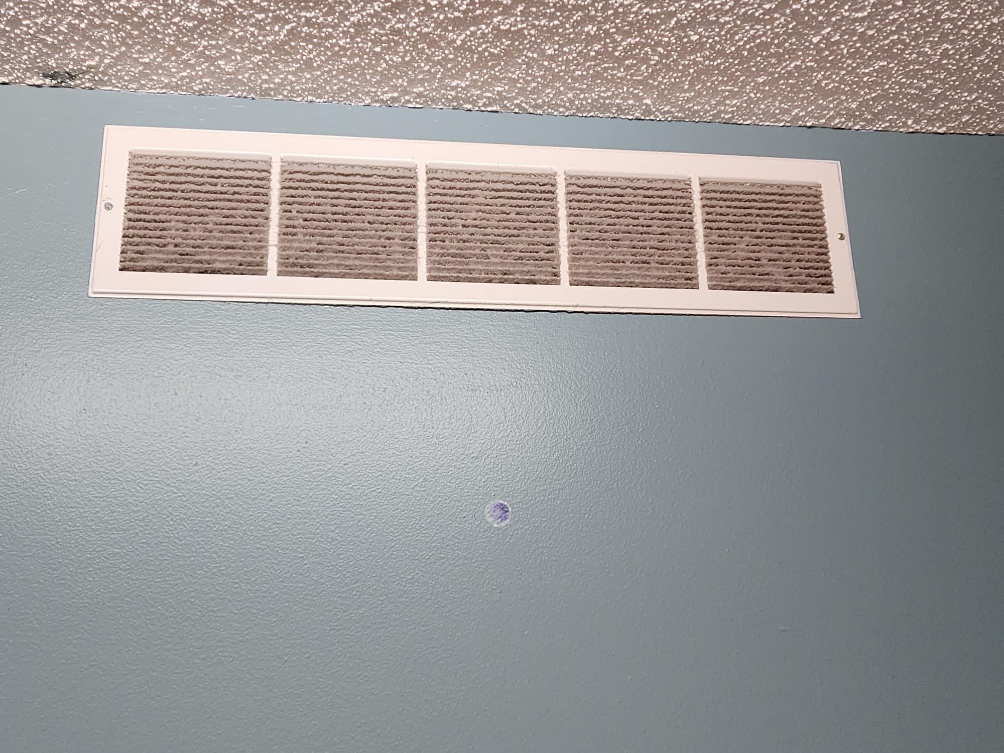 Wall air vent with thick dust buildup before cleaning
